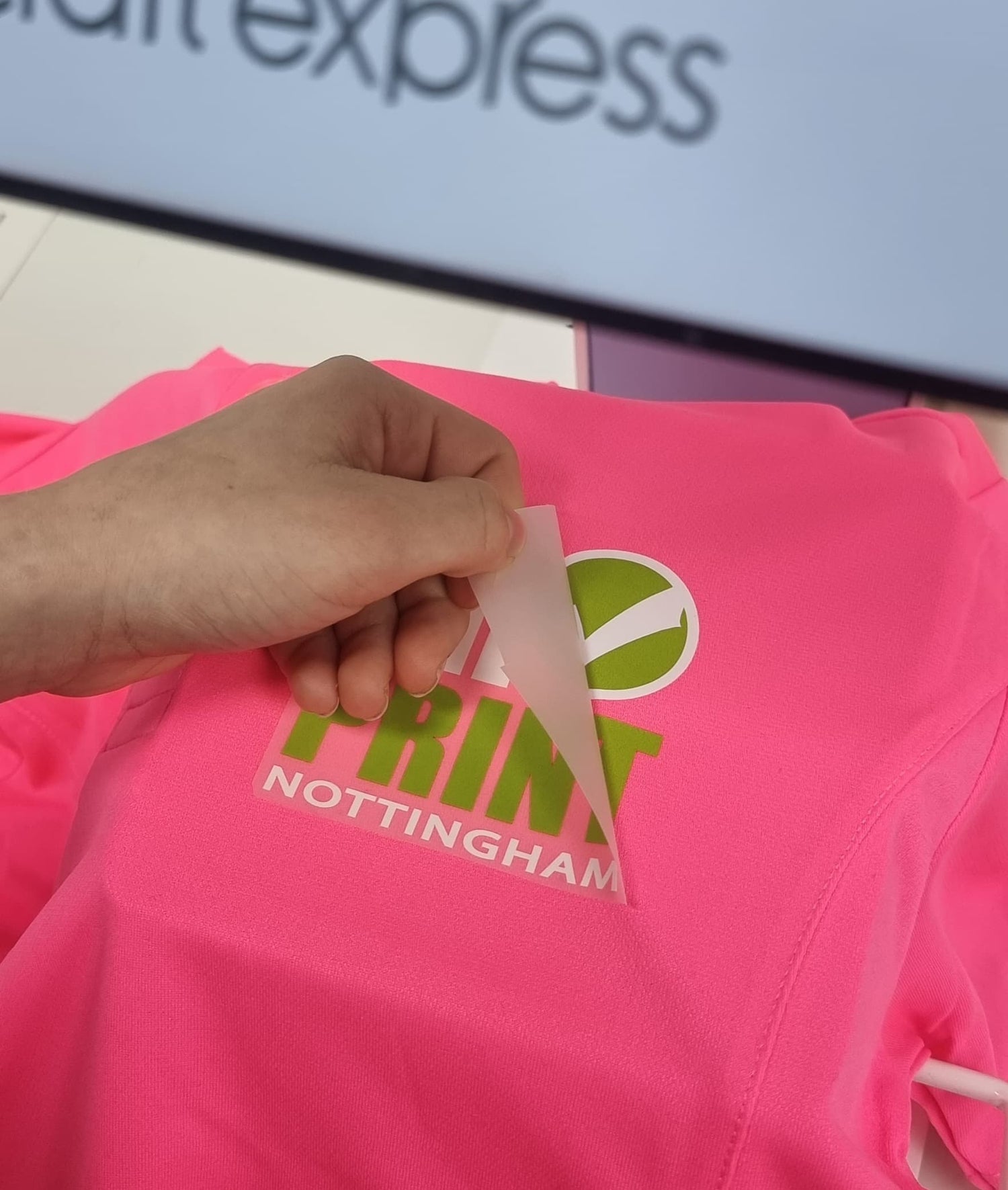 Peeling DTF transfer off a pink hoodie showing Nottingham Print design - DTF Print Online